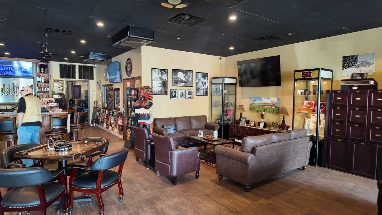 Leather couches and a card table near the bar, with framed photos on the wall.